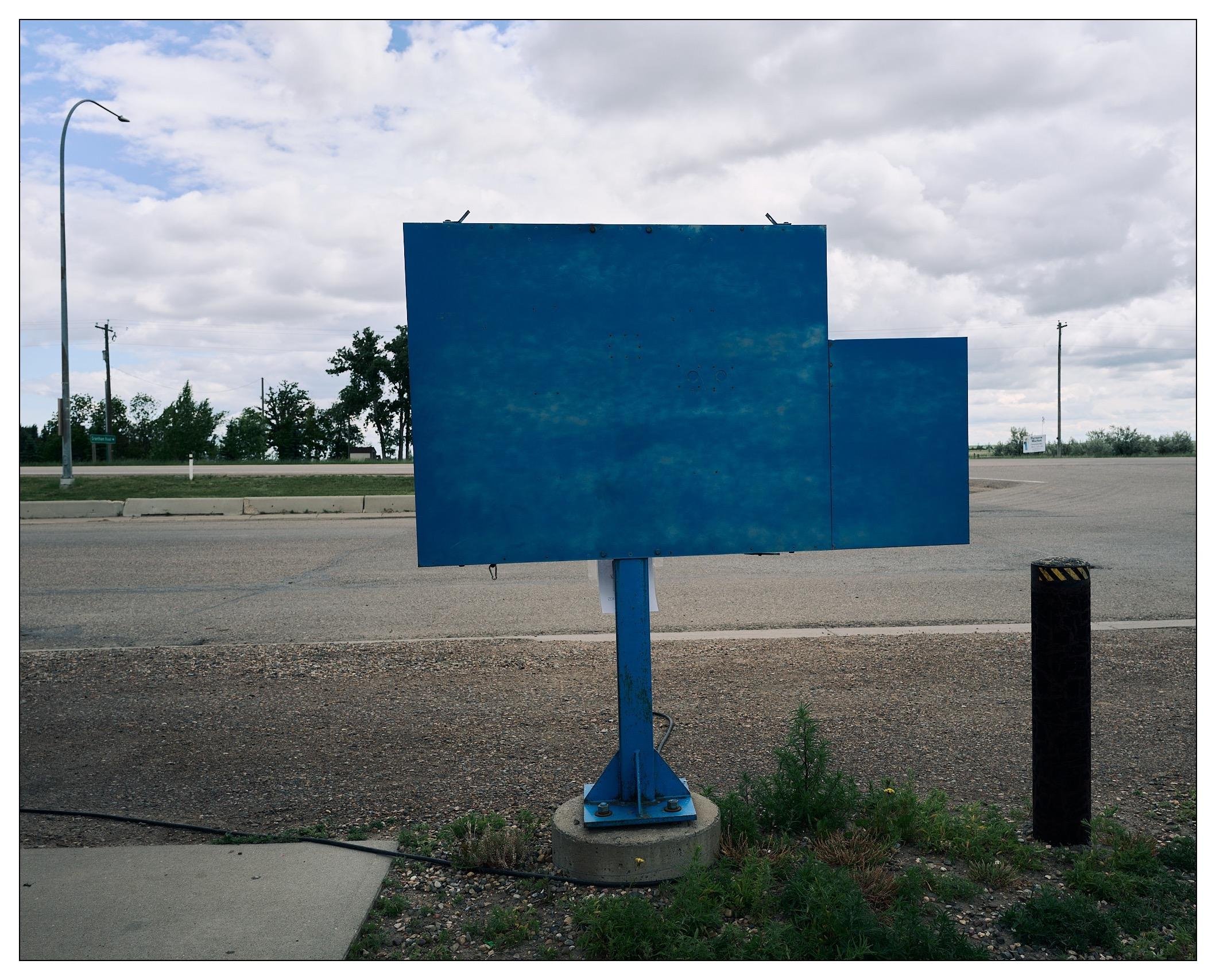 Back side of the menu sign, a solid blue.  Past it is a service road and the highway.
