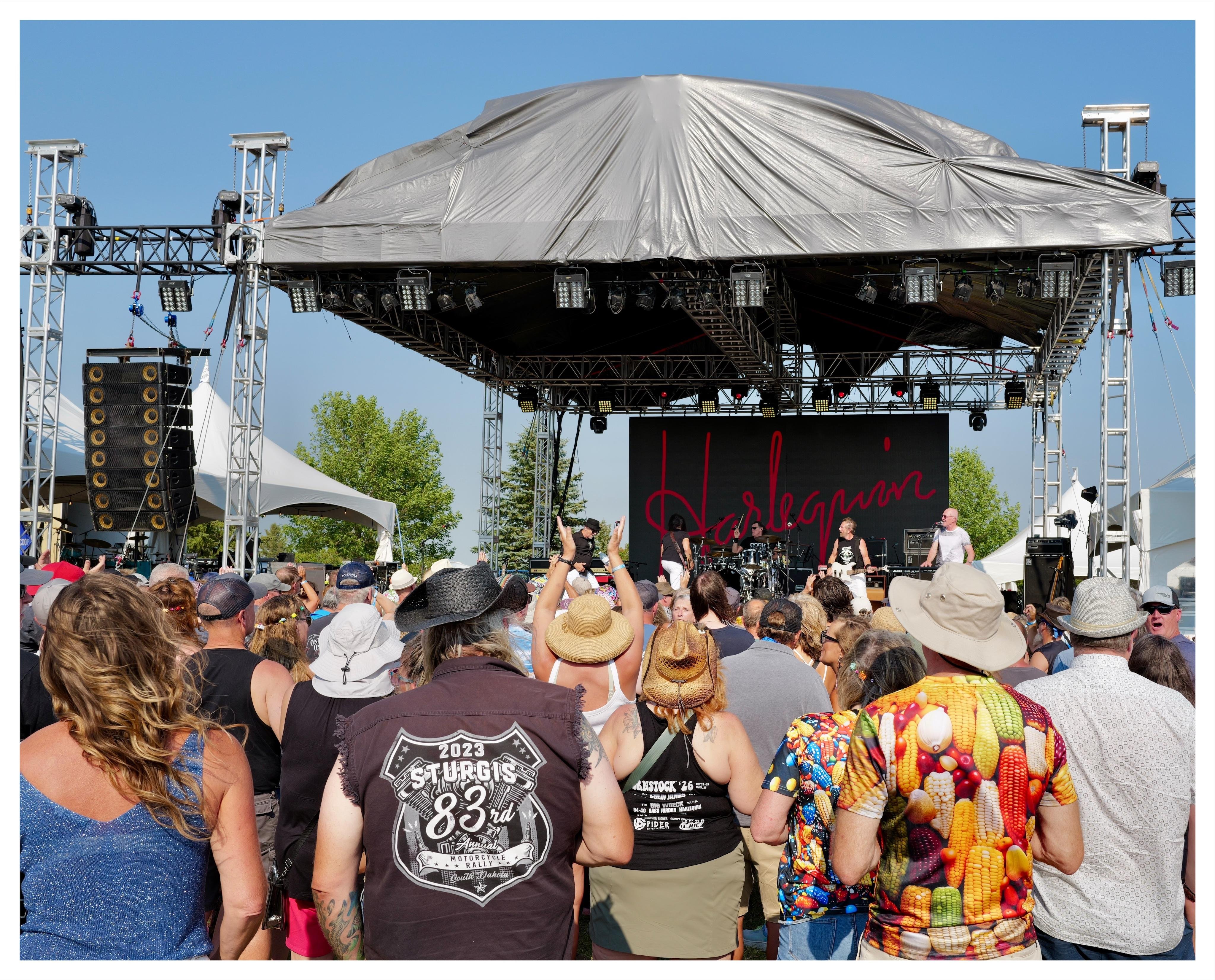 Crowd watching Harlequin perform at corn stock 26 festival in Taber, Alberta.  One person is clapping over their head, squishing guitar player.