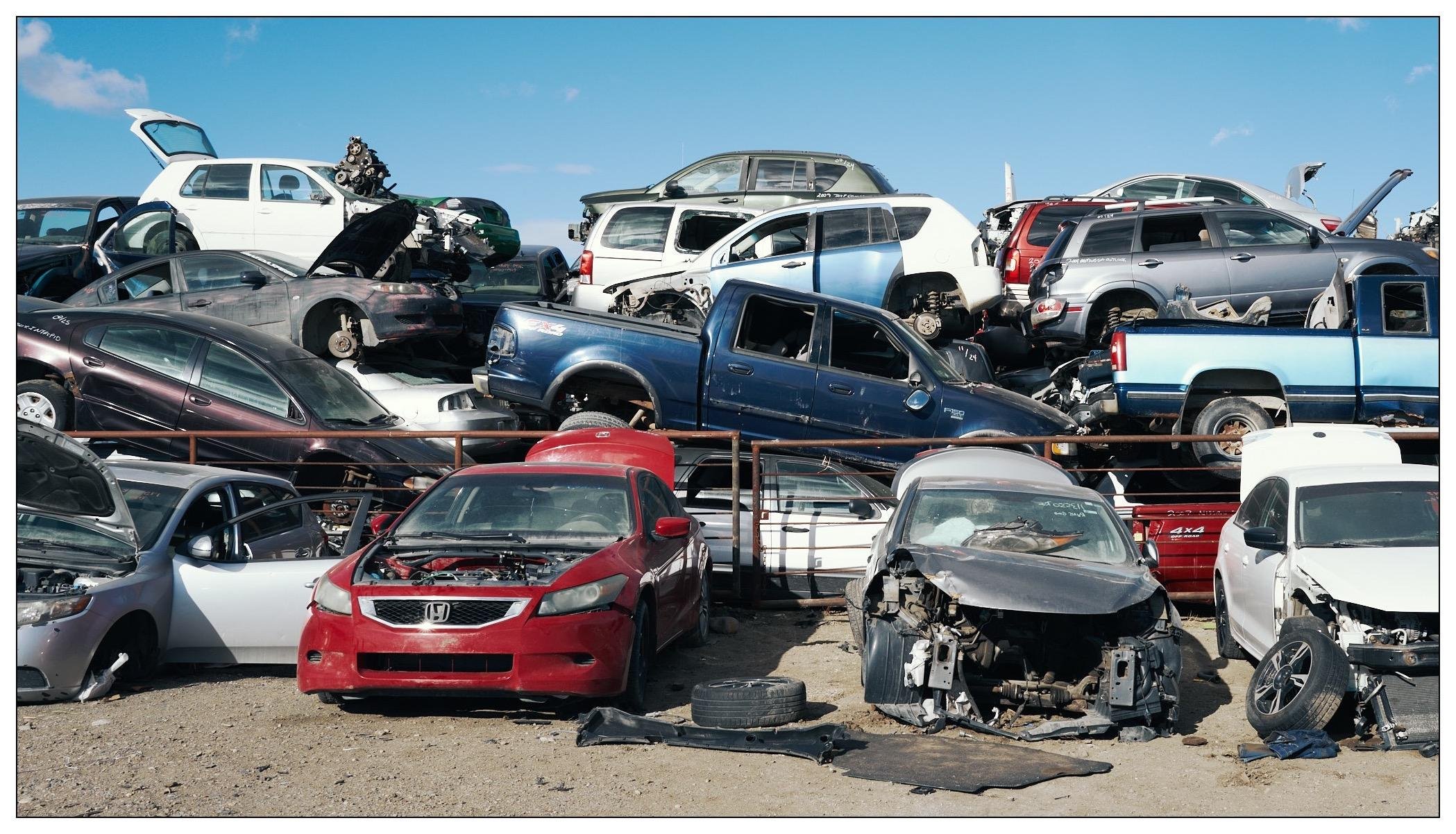 A pile of vehicles at the junk yard.  Literally, a big pile of cars and trucks in a tall pile.